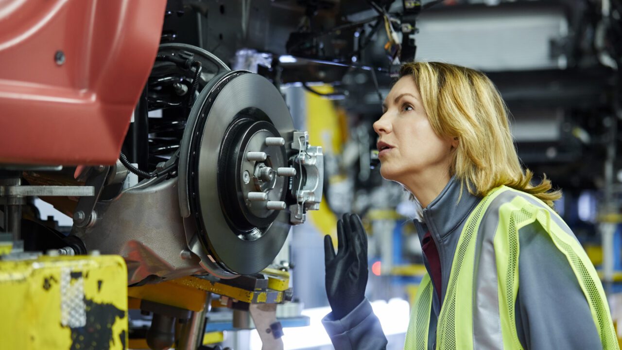 Blond female engineer checking vehicle at factory